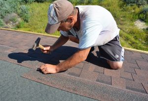 Roofing contractor repairing asphalt shingle roof