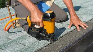 Roofing contractor repairing an asphalt shingle roof.